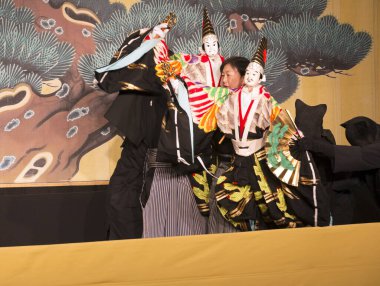 Kimliği belirsiz insanlar Japon tarzında tiyatro sahnelerinde oynuyorlar.