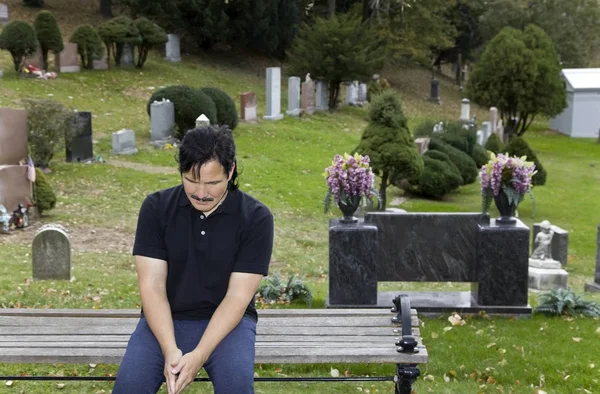 Latino Man Zit Begraafplaats Bankje Met Hoofd Verlaagd — Stockfoto