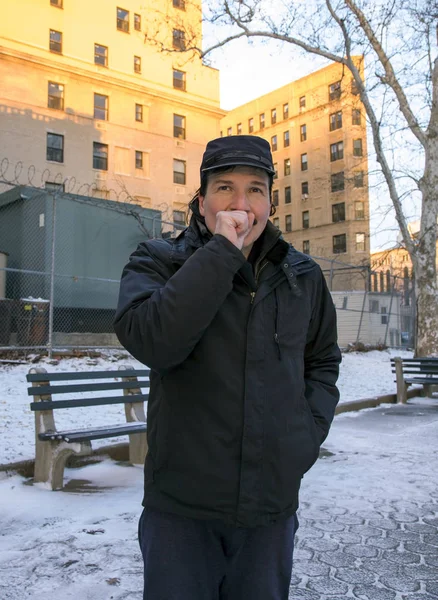 Man warming hand with breath while outdoors in winter