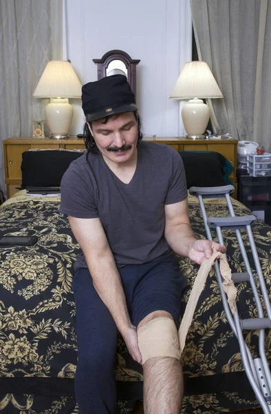 Hombre hispano envolviendo vendaje sobre articulación de rodilla —  Fotos de Stock