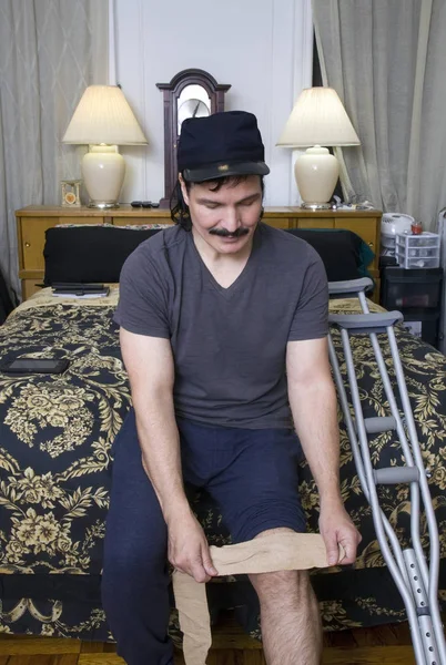 Латиноамериканец надевает повязку на колено в спальне — стоковое фото