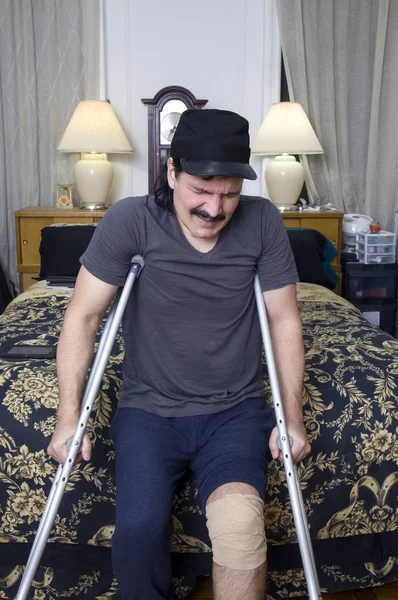 Homem hispânico com muletas e expressão de dor — Fotografia de Stock