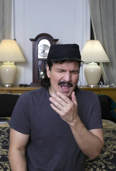 Hispanic man about to sneeze in his bedroom