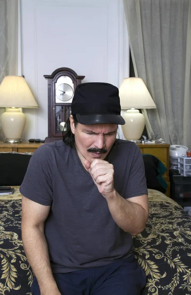 Hispanic man sitting on bed and coughing — Stock Photo, Image