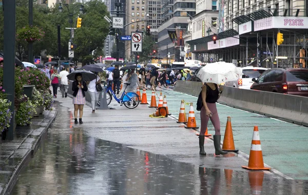 Menschen gehen bei Regen mit Pfützen auf Straßen — Stockfoto