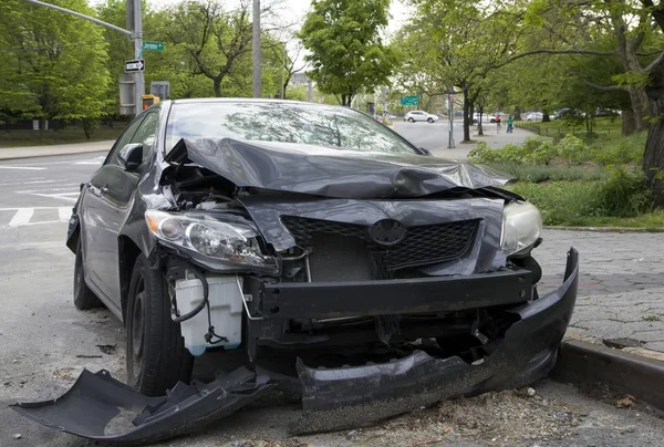 Vehicle parked on curb showing damage from a wreck — Stock Photo, Image