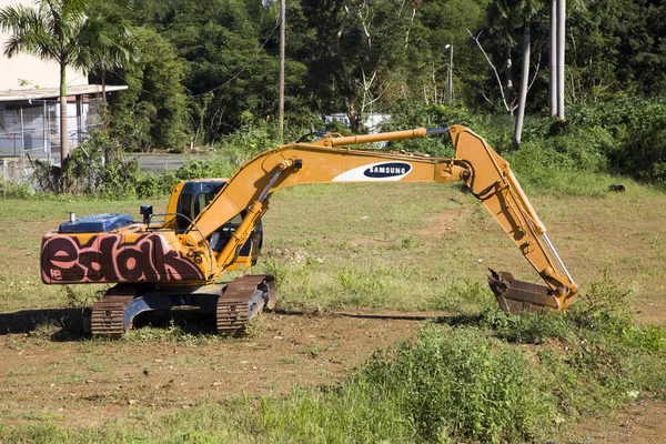 Parked heavy construction excavator with graffitii on grass Baya — Stock Photo, Image