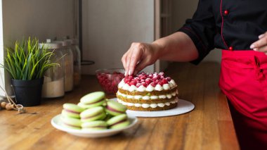Kırmızı-siyah iş üniformalı pudra kek Çilek mutfak ile donatır. Pastacı, kek, pişirme. 