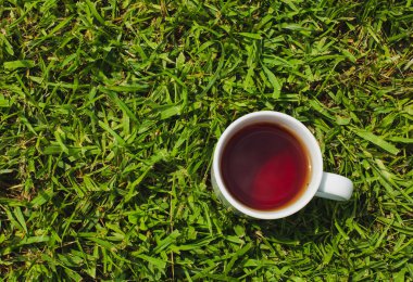 Sıcak siyah çay yeşil çim adam üzerinde beyaz kupa