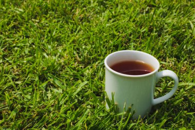 Sıcak siyah çay yeşil çim adam üzerinde beyaz kupa