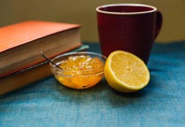 Siyah çay limonlu, yarım limon, kitaplar ve limon reçel bir tekstil arka plan üzerinde. Sonbahar konsepti