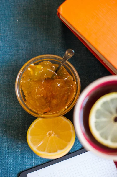 Black Tea with Lemon, Half a Lemon, Books and Lemon Jam  on a Textile  Background. Autumn Concept