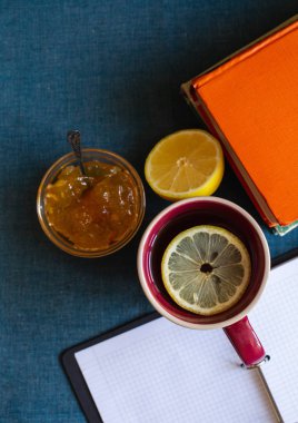 Siyah çay limonlu, yarım limon, kitaplar ve limon reçel bir tekstil arka plan üzerinde. Sonbahar konsepti