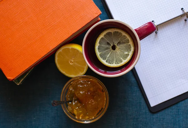 Black Tea with Lemon, Half a Lemon, Books and Lemon Jam  on a Textile  Background. Autumn Concept