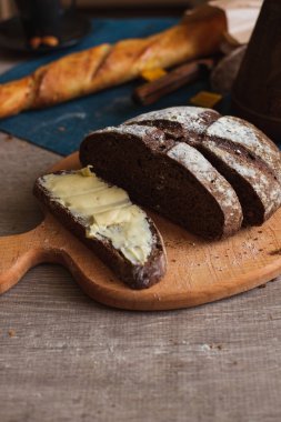 Organik tam buğday karanlık ekmek taze ev yapımı tereyağı ile. Bir dilim ekmek ve tereyağı ve ahşap masası. 