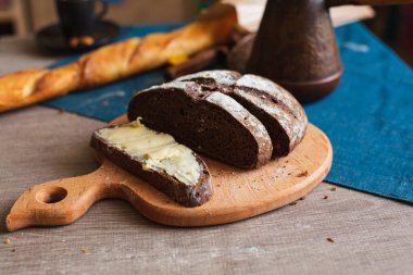 Organik tam buğday karanlık ekmek taze ev yapımı tereyağı ile. Bir dilim ekmek ve tereyağı ve ahşap masası. 