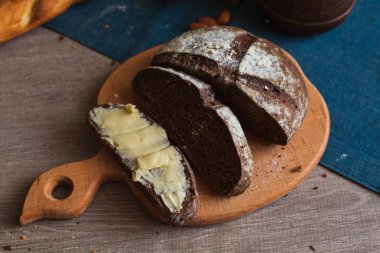 Organik tam buğday karanlık ekmek taze ev yapımı tereyağı ile. Bir dilim ekmek ve tereyağı ve ahşap masası. 