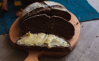 Organik tam buğday karanlık ekmek taze ev yapımı tereyağı ile. Bir dilim ekmek ve tereyağı ve ahşap masası. 