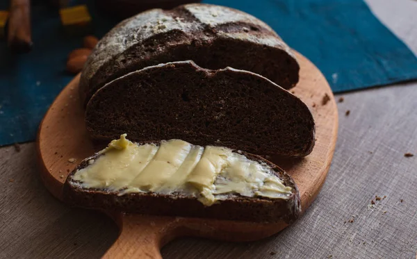 Organik tam buğday karanlık ekmek taze ev yapımı tereyağı ile. Bir dilim ekmek ve tereyağı ve ahşap masası. 