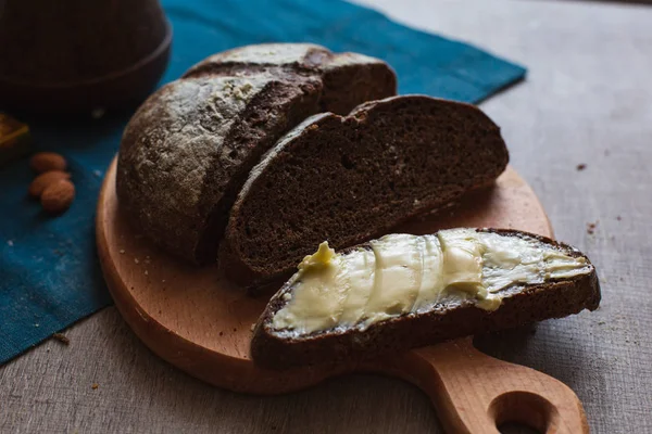 Organik tam buğday karanlık ekmek taze ev yapımı tereyağı ile. Bir dilim ekmek ve tereyağı ve ahşap masası. 