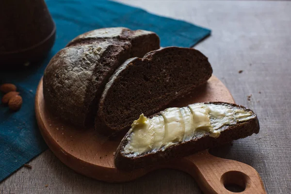 Organik tam buğday karanlık ekmek taze ev yapımı tereyağı ile. Bir dilim ekmek ve tereyağı ve ahşap masası. 