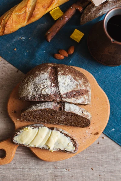 Organik tam buğday karanlık ekmek taze ev yapımı tereyağı ile. Bir dilim ekmek ve tereyağı ve ahşap masası. 