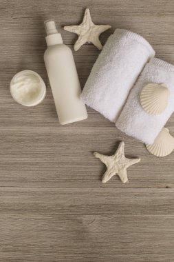 Yumuşak beyaz havlu ve banyo aksesuarları tahta masaya yuvarlandı. Üstten görünüm. Cilt sağlığı kavramı temizlik. Düz yatıyordu