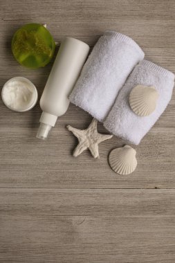 Yumuşak beyaz havlu ve banyo aksesuarları tahta masaya yuvarlandı. Üstten görünüm. Cilt sağlığı kavramı temizlik. Düz yatıyordu