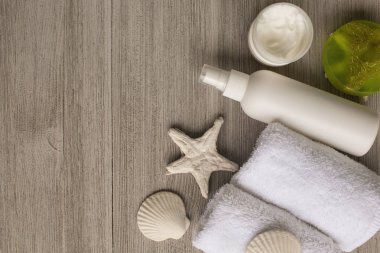 Yumuşak beyaz havlu ve banyo aksesuarları tahta masaya yuvarlandı. Üstten görünüm. Cilt sağlığı kavramı temizlik. Düz yatıyordu