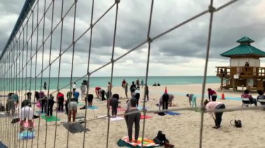 Miami, Fl, Amerika Birleşik Devletleri - 20 Ocak 2019: Grup Yoga sınıf günbatımı kum plaj. Grup pratik Yoga sahilde insan. Dolunay Miami