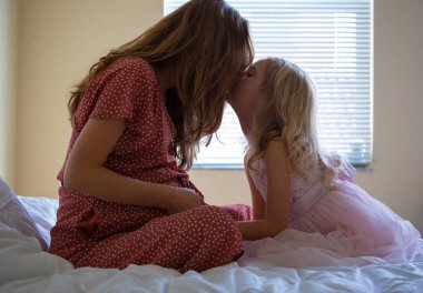 Genç hamile anne oynarken onun küçük komik kızı süre oturan bir kanepe ile