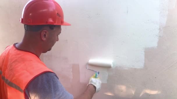 壁を描くローラーで仕事でヘルメットの画家の男 画家の家のコンセプト — ストック動画
