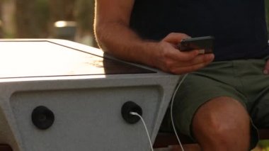 Usb Outdoors üzerinden Cep Telefonu Şarj Man. Sokakta Güneş Paneli ile Bench Kamu Şarj. Alternatif Elektrik Kaynağı. Modern teknoloji kavramı.