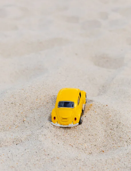 Gelber Kleinwagen auf sandigem, natürlichem Hintergrund. Sommerferienkonzept — Stockfoto