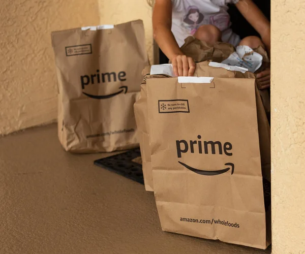 Daire kapısında Amazon Prime paketi. Paketleri ile yerleşik eller. Amazon dünyanın en büyük perakendecisi. Telifsiz Stok Imajlar