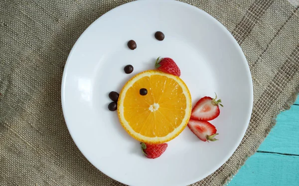 Fruit on plate with orange and strawberry, form fish on ocean