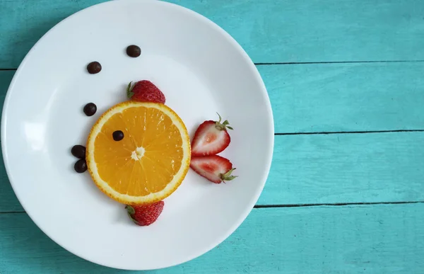 Fruit on plate with orange and strawberry, form fish on ocean