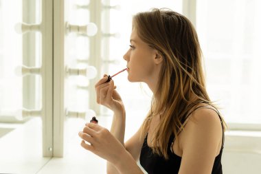 Genç güzel kız onun dudakları parlak bir oda aynaya yakınındaki boyalar