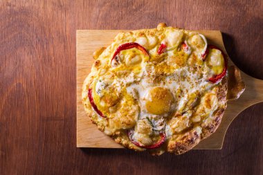 ahşap bir tahta üzerinde bir tortilla üzerinde sebze ile peynir ile pişmiş yumurta.