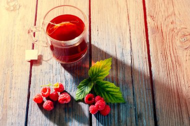 olgun ahududu ve yeşil taze demlenmiş yaprakları ile çay ahşap bir masada sağlık için sağlıklı