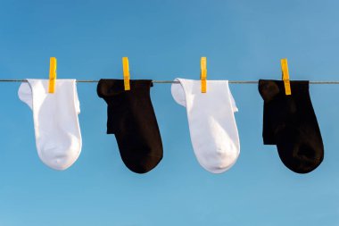 dört yeni, temiz, yıkanmış beyaz ve siyah çorap sarı clothespins ile bir ip üzerinde asmak.