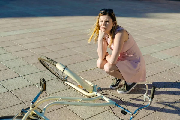 Девушка упала и сломала велосипед. эмоции испугались и не знают, что делать — стоковое фото