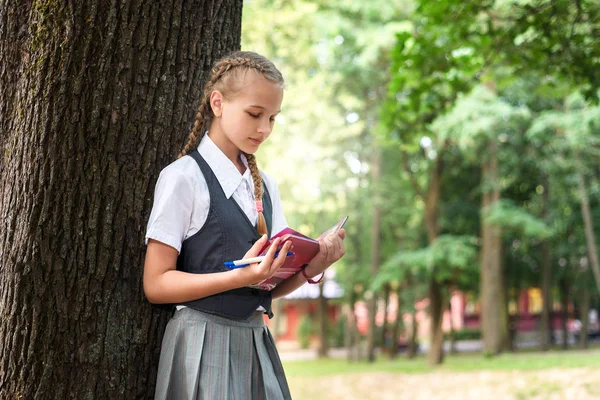 Μαθήτρια έφηβος διαβάζοντας ένα βιβλίο σε ένα πάρκο κοντά σε ένα δέντρο. — Φωτογραφία Αρχείου