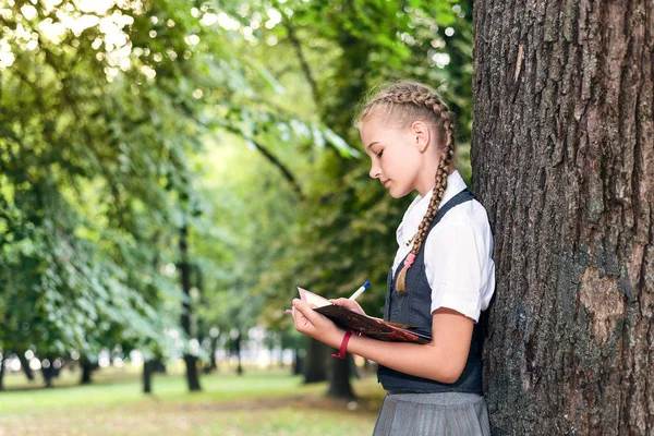 Школьница-подросток читает книгу в парке рядом с деревом . — стоковое фото