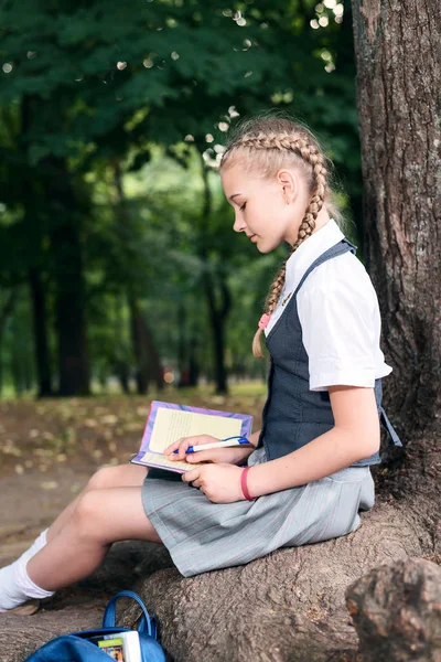 Μαθήτρια έφηβος διαβάζοντας ένα βιβλίο σε ένα πάρκο κοντά σε ένα δέντρο. — Φωτογραφία Αρχείου