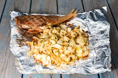 sebze ile pişmiş balık ahşap bir folyo yatıyor