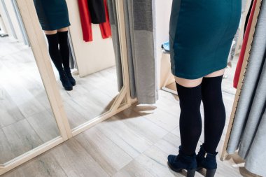 Genç ve güzel bir kız butikte yeni yeşil elbiseler deniyor..