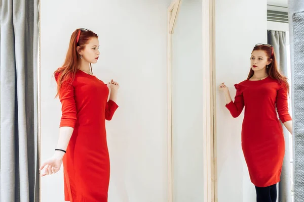 Красивая молодая девушка примеряет красное платье в магазине. Красотка, позирующая по прихоти . — стоковое фото