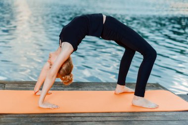 kız rive tarafından gün batımında yoga yapıyor