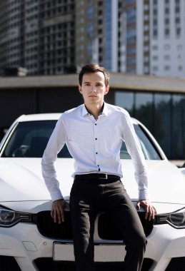 Genç ve yakışıklı bir adam arabanın yanında.